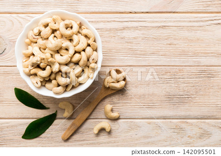 cashew nuts in wooden bowl on table background. top view. Space for text Healthy food cashew nuts in wooden bowl on table background. top view. Space for text Healthy food 142095501