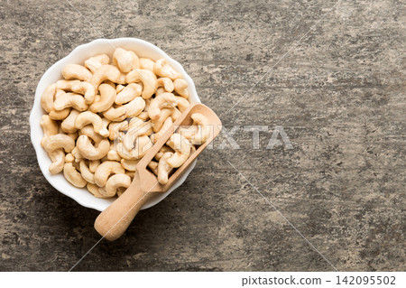 cashew nuts in wooden bowl on table background. top view. Space for text Healthy food cashew nuts in wooden bowl on table background. top view. Space for text Healthy food 142095502
