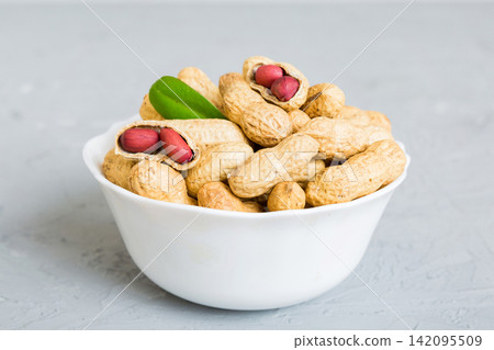 Fresh healthy peanuts in bowl on colored table background. Top view Healthy eating bertholletia concept. Super foods Fresh healthy peanuts in bowl on colored table background. Top view Healthy eating bertholletia concept. Super foods 142095509