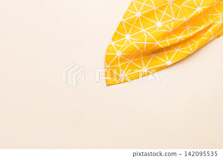top view with yellow empty kitchen napkin isolated on table background. Folded cloth for mockup with copy space, Flat lay. Minimal style top view with yellow empty kitchen napkin isolated on table background. Folded cloth for mockup with copy space, Flat lay. Minimal style 142095535