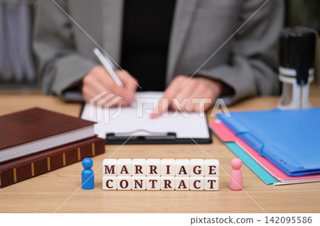 Signing a marriage contract with colorful blocks and documents on a wooden desk Signing a marriage contract with colorful blocks and documents on a wooden desk 142095586