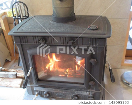 The flames of the wood-burning stove warm the room. The flames of the wood-burning stove warm the room. 142095593