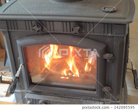 The flames of the wood-burning stove warm the room. The flames of the wood-burning stove warm the room. 142095595