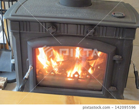 The flames of the wood-burning stove warm the room. The flames of the wood-burning stove warm the room. 142095596