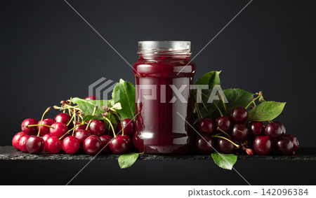 Cherry jam and fresh berries on a black background. Cherry jam and fresh berries on a black background. 142096384