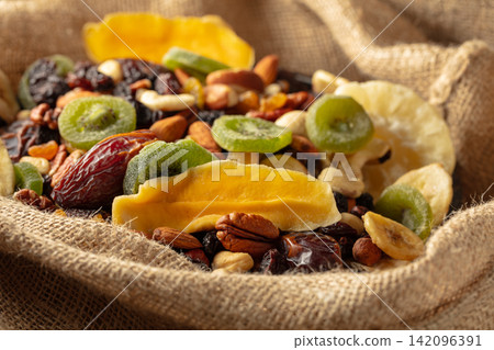 Dried tropical fruits and nuts in burlap bag. Dried tropical fruits and nuts in burlap bag. 142096391