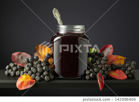 Chokeberry jam and fresh berries with leaves. Chokeberry jam and fresh berries with leaves. 142096409