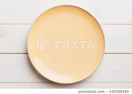 Top view of empty orange plate on wooden background. Empty space for your design 142096480