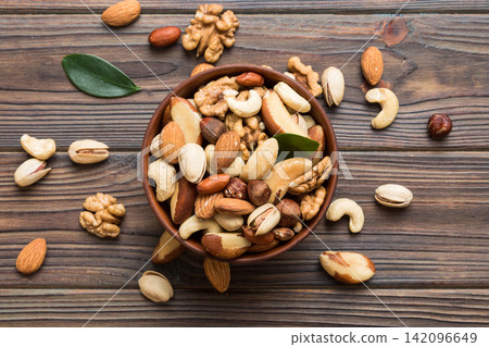 mixed nuts in bowl. Mix of various nuts on colored background. pistachios, cashews, walnuts, hazelnuts, peanuts and brazil nuts mixed nuts in bowl. Mix of various nuts on colored background. pistachios, cashews, walnuts, hazelnuts, peanuts and brazil nuts 142096649