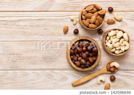 Assortment of nuts in wooden bowl on colored table. Cashew, hazelnuts, walnuts, almonds. Mix of nuts Top view with copy space Assortment of nuts in wooden bowl on colored table. Cashew, hazelnuts, walnuts, almonds. Mix of nuts Top view with copy space 142096690