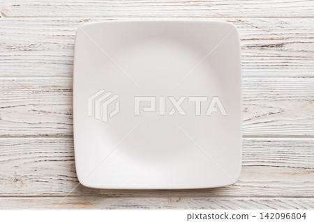 Top view of empty square plate on wooden background. Empty space for your design Top view of empty square plate on wooden background. Empty space for your design 142096804