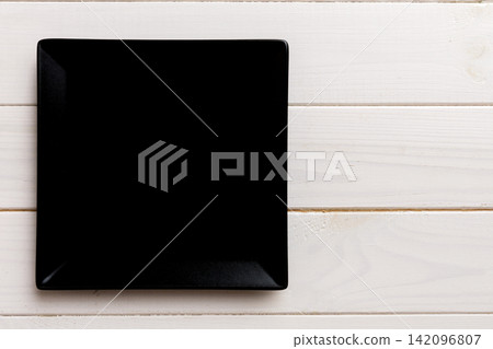 Top view of empty square plate on wooden background. Empty space for your design Top view of empty square plate on wooden background. Empty space for your design 142096807