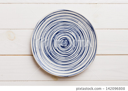 Top view of empty colorful plate on wooden background. Empty space for your design Top view of empty colorful plate on wooden background. Empty space for your design 142096808