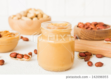 Bowl of peanut butter and peanuts on table background. top view with copy space. Creamy peanut pasta in small bowl Bowl of peanut butter and peanuts on table background. top view with copy space. Creamy peanut pasta in small bowl 142096955