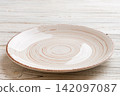 Perspective view of empty light plate on wooden background. Empty space for your design 142097087