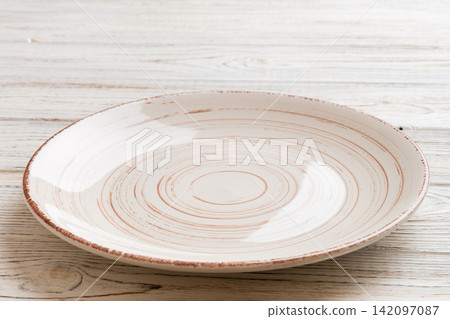 Perspective view of empty light plate on wooden background. Empty space for your design Perspective view of empty light plate on wooden background. Empty space for your design 142097087