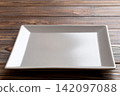 Perspective view of empty square plate on wooden background. Empty space for your design 142097088