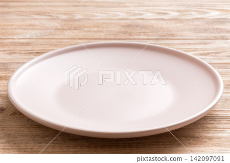 Perspective view of empty light plate on wooden background. Empty space for your design 142097091