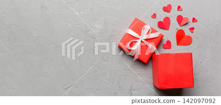 Happy valentines day opened heart shape gift box with small hearts, on colored background, valentines day card - top view concept 142097092