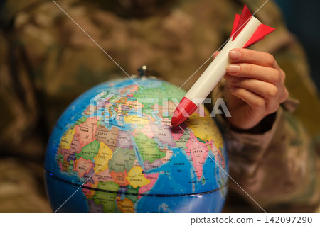 Military officer woman holds rocket over Earth globe model Military officer woman holds rocket over Earth globe model 142097290