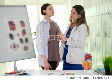 Woman doctor checks female patient chest at appointment Woman doctor checks female patient chest at appointment 142097871