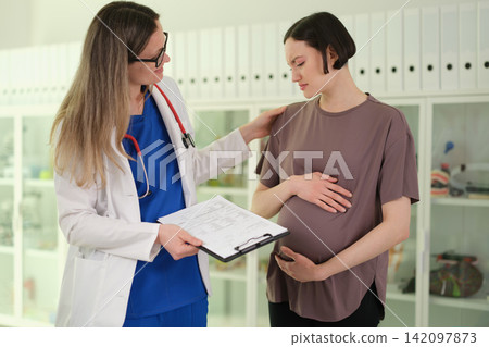 Woman doctor encourages pregnant patient before clinic checkup Woman doctor encourages pregnant patient before clinic checkup 142097873