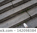 The feet of white sneakers walking on the stone steps 142098384