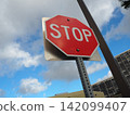 A red STOP sign against a blue sky. 142099407