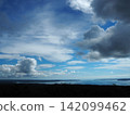 A seascape with a blue sky and large clouds. 142099462