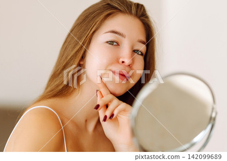 Beautiful woman with small mirror enjoys her reflection. Concept of beauty, naturalness. Lifestyle. Beautiful woman with small mirror enjoys her reflection. Concept of beauty, naturalness. Lifestyle. 142099689