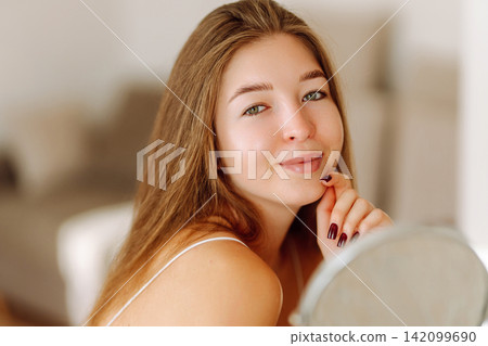 Beautiful woman with small mirror enjoys her reflection. Concept of beauty, naturalness. Lifestyle. Beautiful woman with small mirror enjoys her reflection. Concept of beauty, naturalness. Lifestyle. 142099690