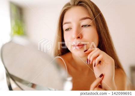 Beautiful woman with small mirror enjoys her reflection. Concept of beauty, naturalness. Lifestyle. Beautiful woman with small mirror enjoys her reflection. Concept of beauty, naturalness. Lifestyle. 142099691
