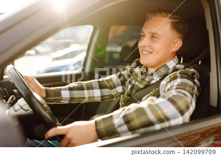 Young man in car smiling and looking at camera. Buying, renting car. Car travel, lifestyle concept. Young man in car smiling and looking at camera. Buying, renting car. Car travel, lifestyle concept. 142099709