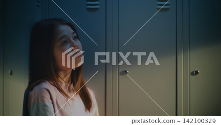 Pensive Female High School Student Sitting by School Lockers During Peaceful Break Pensive Female High School Student Sitting by School Lockers During Peaceful Break 142100329