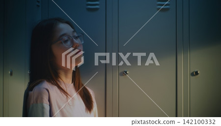 Pensive Female High School Student Sitting by School Lockers During Peaceful Break Pensive Female High School Student Sitting by School Lockers During Peaceful Break 142100332