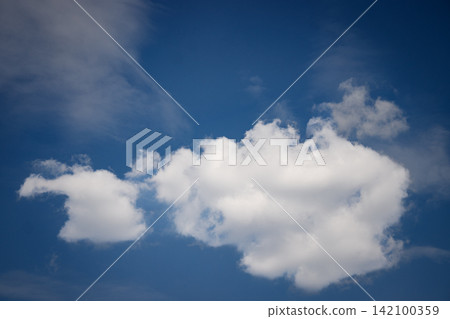 White clouds drifting across a deep blue sky on a sunny day White clouds drifting across a deep blue sky on a sunny day 142100359