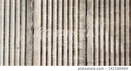 Grooved vertical concrete panels with a weathered appearance and visible joint lines. 142100494