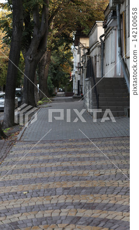 Quiet sidewalk scene in a city during autumn. Quiet sidewalk scene in a city during autumn. 142100658