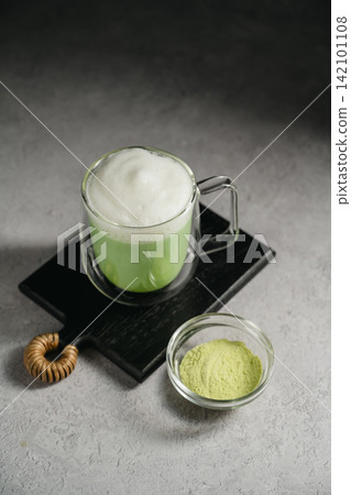 Matcha latte with green tea powder and frothy milk, matcha preparation and healthy beverage concept Matcha latte with green tea powder and frothy milk, matcha preparation and healthy beverage concept 142101108
