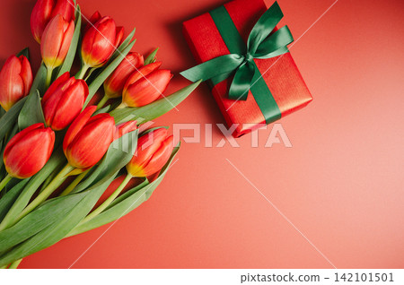 Mothers' day. Red tulips with gift box. Easter holiday. Red background, copy space. Mothers' day. Red tulips with gift box. Easter holiday. Red background, copy space. 142101501