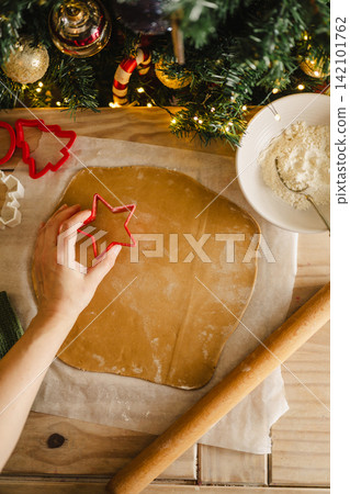 Holiday background. Rolling pin, female hands and raw rolled dough, cooking Christmas gingerbread cookies. Top view Holiday background. Rolling pin, female hands and raw rolled dough, cooking Christmas gingerbread cookies. Top view 142101762
