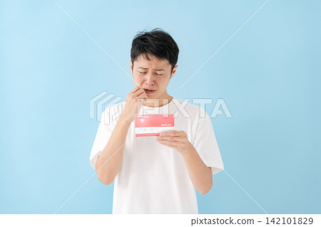一位中年男子一邊看著存摺一邊沉思。 一位中年男子一邊看著存摺一邊沉思。 142101829