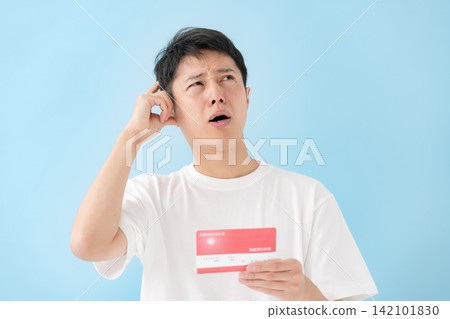 一位中年男子一邊看著存摺一邊沉思。 一位中年男子一邊看著存摺一邊沉思。 142101830