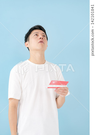 一位中年男子一邊看著存摺一邊沉思。 一位中年男子一邊看著存摺一邊沉思。 142101841