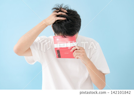 一位中年男子一邊看著存摺一邊沉思。 一位中年男子一邊看著存摺一邊沉思。 142101842
