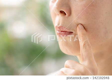 一位女子憂心忡忡地撫摸著自己的臉頰。 142102048