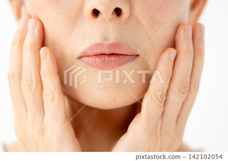 A woman touches her cheek, looking troubled. (Front view) A woman touches her cheek, looking troubled. (Front view) 142102054