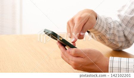 A man operating a smartphone A man operating a smartphone 142102201