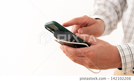 A man operating his smartphone while it's charging. A man operating his smartphone while it's charging. 142102208