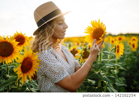 Happy woman posing in a field of sunflowers in hat. Fashion, lifestyle, travel and vacations concept Happy woman posing in a field of sunflowers in hat. Fashion, lifestyle, travel and vacations concept 142102254